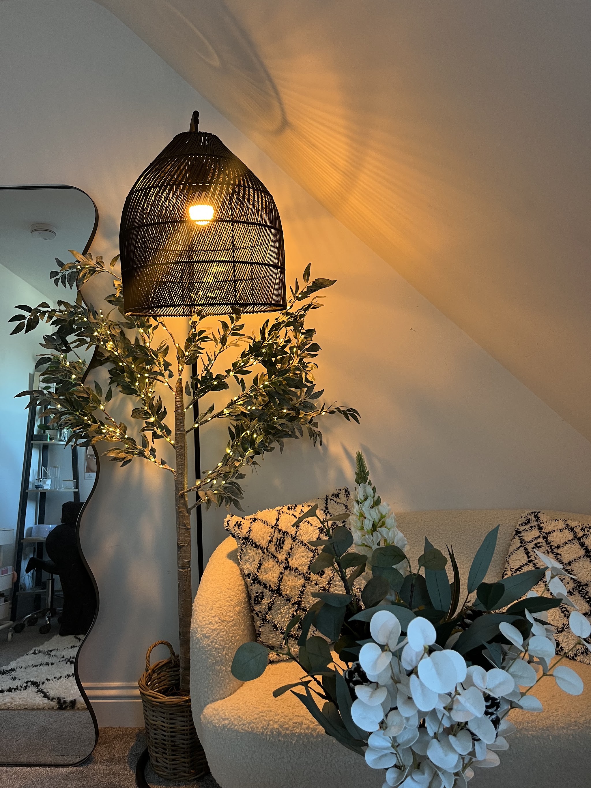 Corner of the salon with rattan lamp, boucle chair and eucalyptus
